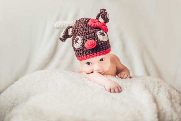 Happy smiling infant baby boy portrait dressed in christmas deer crocheted hat winter holidays