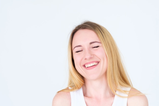 happy smiling joyful blonde woman on white wall.