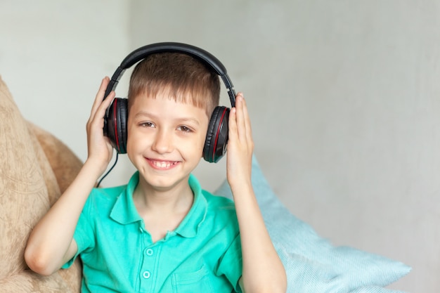 Happy smiling kid boy in headphones listen to music