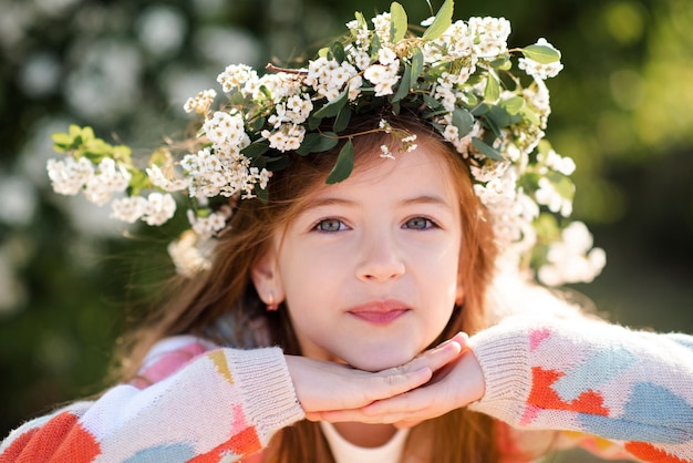 Happy smiling kid girl wear knit colorful sweater and floral wreath hairstyle with flowers