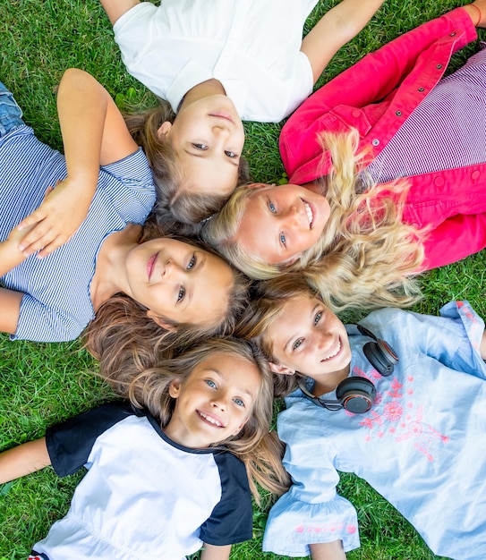 Bambini sorridenti felici che guardano la telecamera sull'erba topview