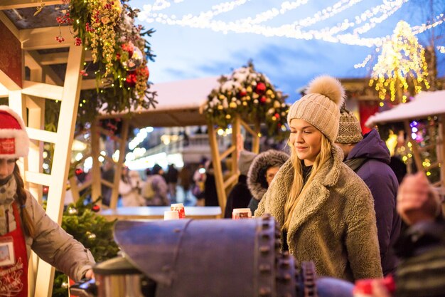 Photo happy smiling lady poses at a street holiday fair holding lollipops in her hands