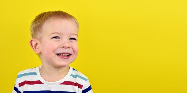 Happy smiling little boy on color background portrait of a beautiful european boy two years old on a yellow background copy space for text