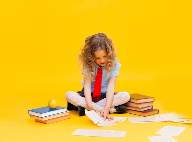 Happy smiling little girl in a school uniform sits with books