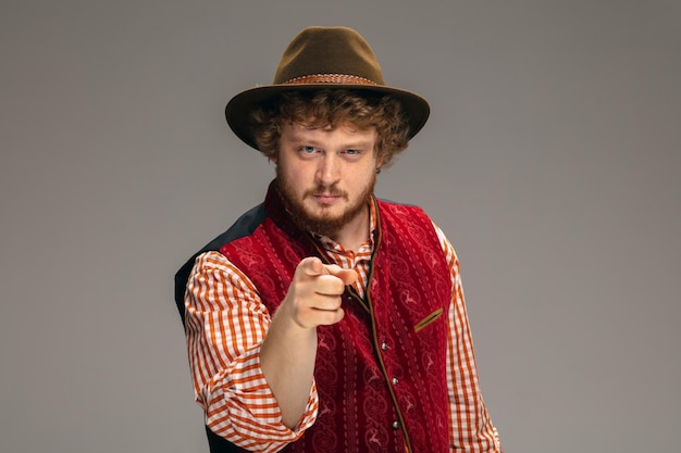 Happy smiling man dressed in traditional austrian or bavarian costume gesturing isolated on grey