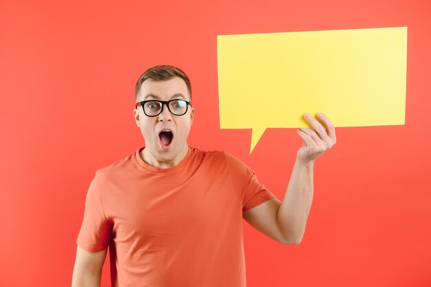 Happy smiling man holding yellow bubble speech looking at camera over red background