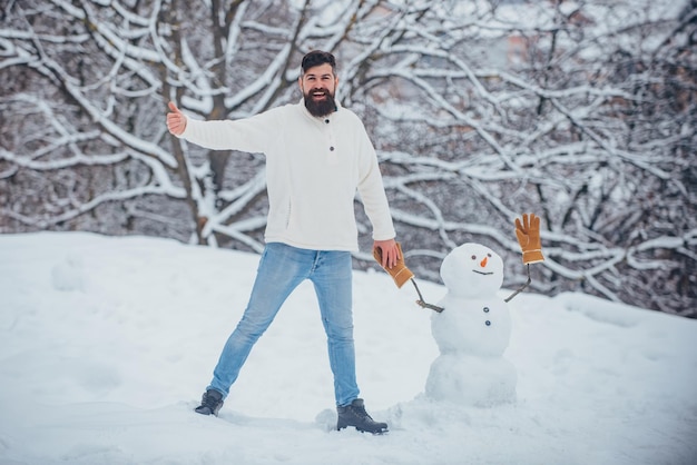 Happy smiling man make snowman on sunny winter day Winter man Fashion portrait of young model man in