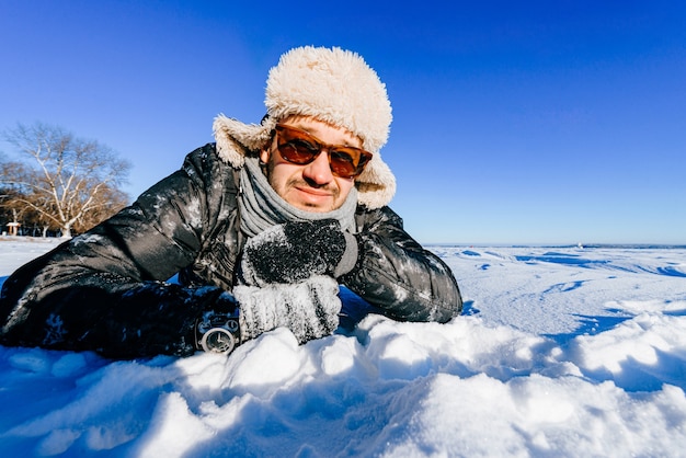 Счастливый улыбающийся человек в солнцезащитных очках позирует в снегу на открытом воздухе