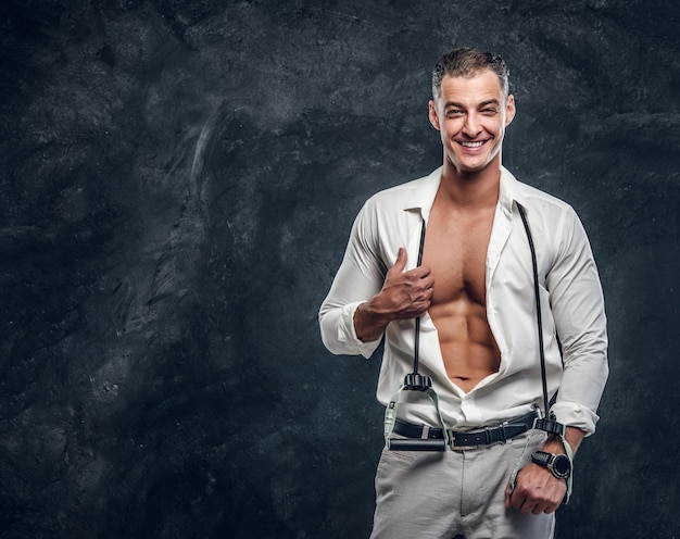 Happy smiling man in white shirt is showing his perfect six pack when opened shirt.