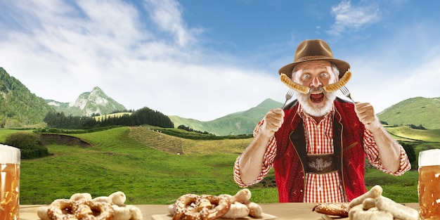 The happy smiling man with beer dressed in traditional Austrian or Bavarian costume