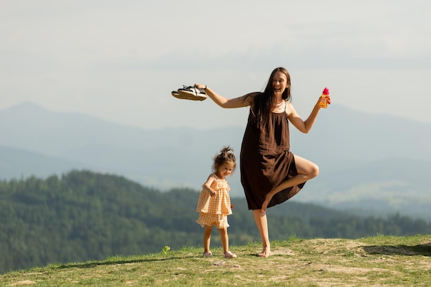 Photo happy smiling mom with little daughter doing yoga and playing at mountain at hill standing in pose