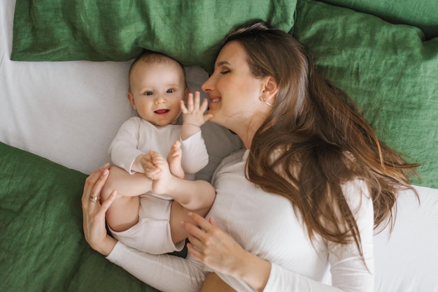 Happy smiling mother and child lying on the bed at home on the bed top view