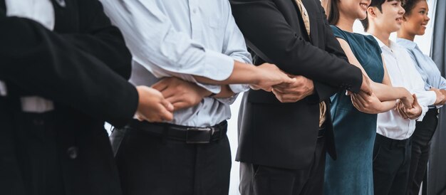 Happy and smiling multiracial office worker hold hand in a line promoting synergy and collaboration for business success Diverse professional office worker bond at modern workplace Concord