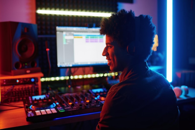Счастливый улыбающийся музыкальный продюсер в студии звукозаписи