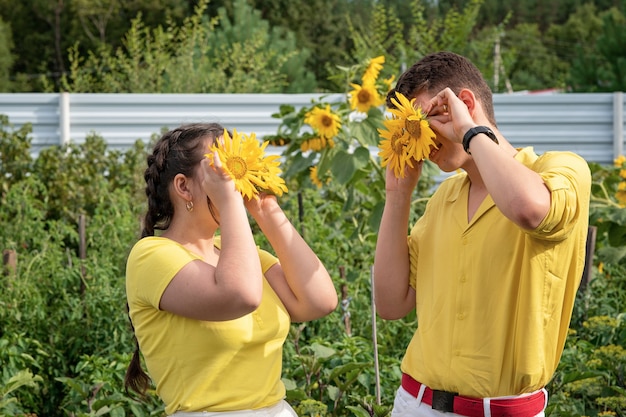 Happy smiling people holding sunflowers near their eyes