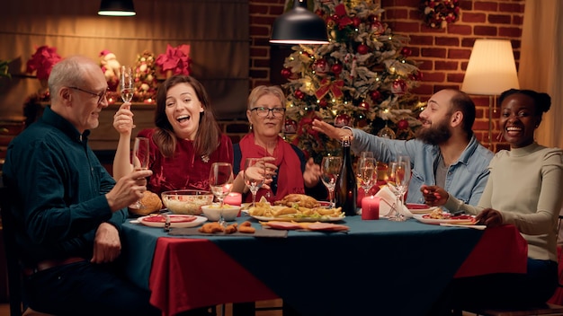 Photo happy smiling people laughing heartily while talking to camera at christmas dinner. joyful family members celebrating winter holiday together while enjoying time together at home. tripod shot