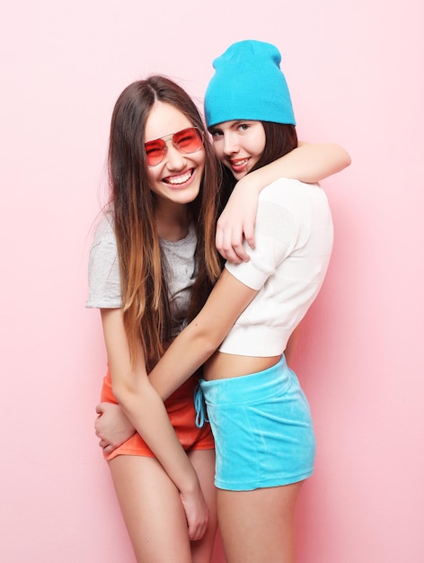 Happy smiling pretty teenage girls or friends hugging over pink