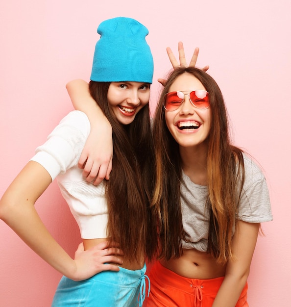 Happy smiling pretty teenage girls or friends hugging over pink