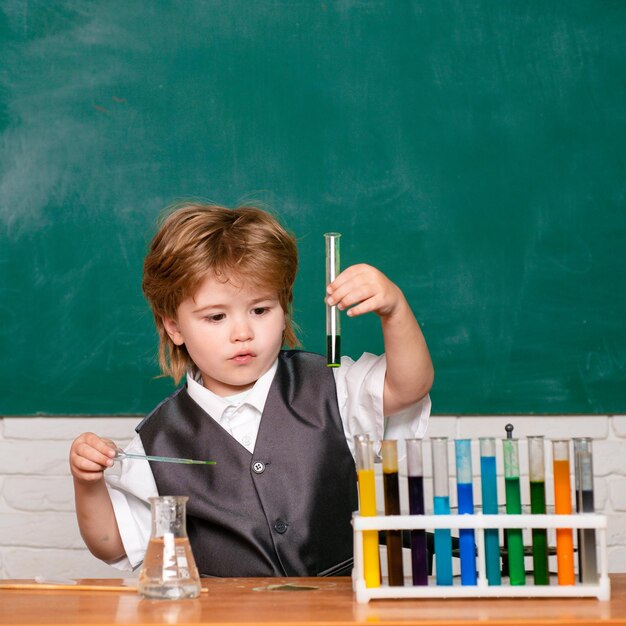 Happy smiling pupil drawing at the desk schoolchild School chemistry lessons Junior year chemistry Blackboard for copy space text Chemistry science School concept