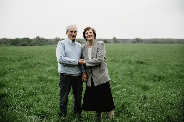 Happy smiling senior couple in love on nature, having fun. Elderly couple on the green field. Cute senior couple walking and hugging in spring forest