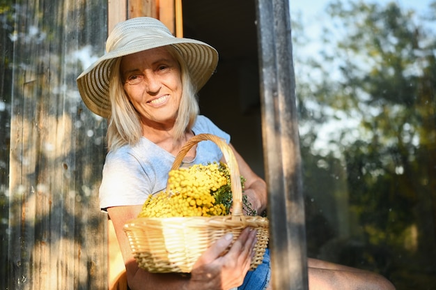 幸せな笑顔の年配の女性が花でポーズ