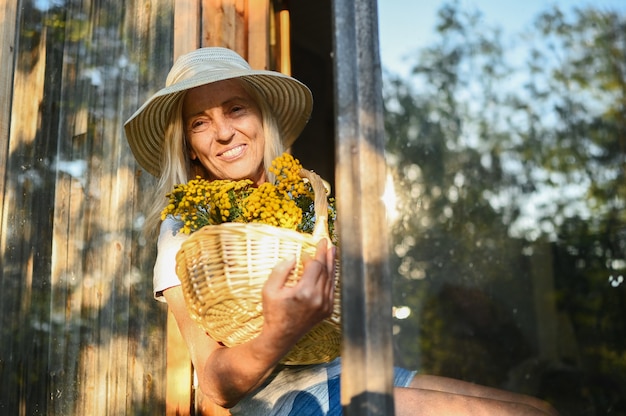 Счастливый улыбающийся старший женщина позирует с цветами