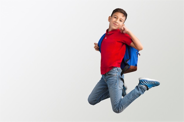 Happy smiling student boy jumping over grey background