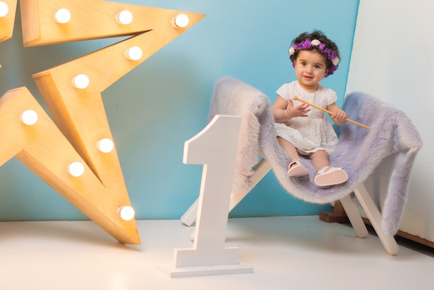 Happy smiling sweet baby girl sitting on armchair with shining light star