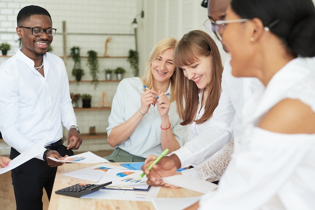 Una squadra sorridente felice di persone multinazionali ride, sorride e si rallegra della vittoria, del contratto firmato o dell'accordo firmato.