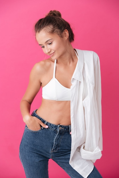 Happy smiling woman in casual clothes holding shirt on her shoulder isolated on the pink wall