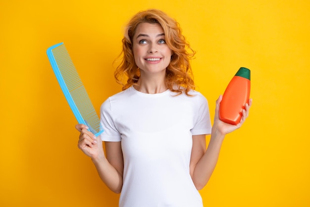 Happy smiling woman hold bottle shampoo and conditioner Funny girl combing hair Redhead woman