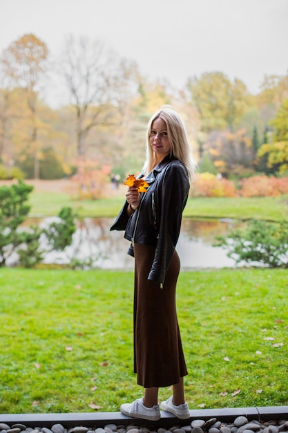 Happy smiling woman holding in her hands yellow maple leaves