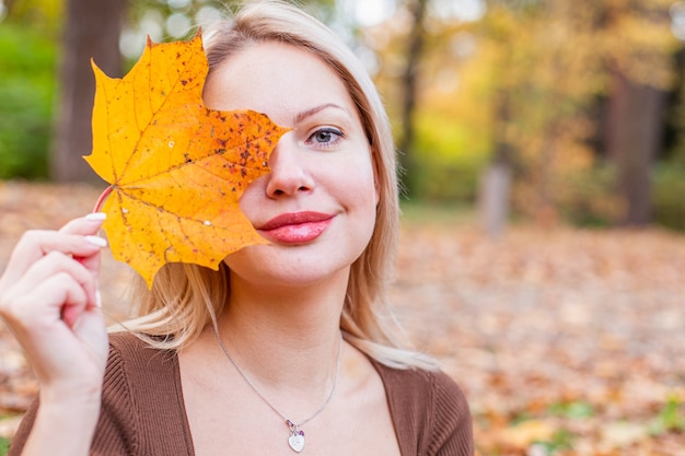 Happy smiling woman holding in her hands yellow maple leaves