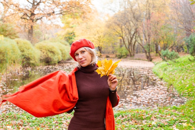 Happy smiling woman holding in her hands yellow maple leaves