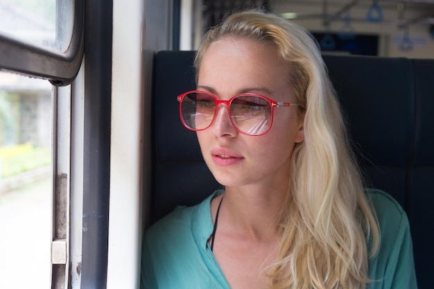 スリランカの鉄道で電車で旅している幸せな笑顔の女性が窓から外を見ています