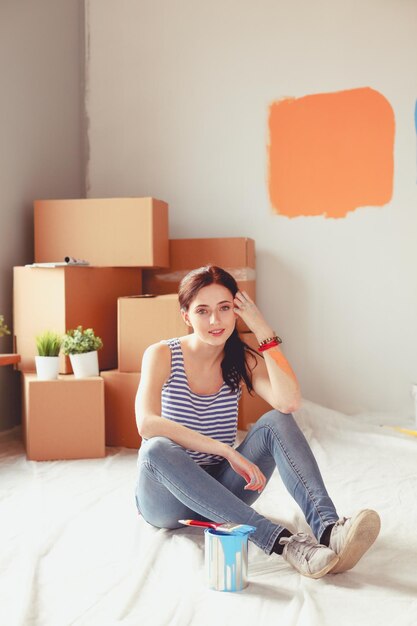 Happy smiling woman painting interior wall of new house Happy smiling woman