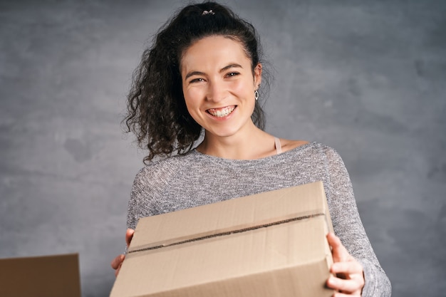 Фото Счастливая улыбающаяся женщина получила большую коробку, держа в руках