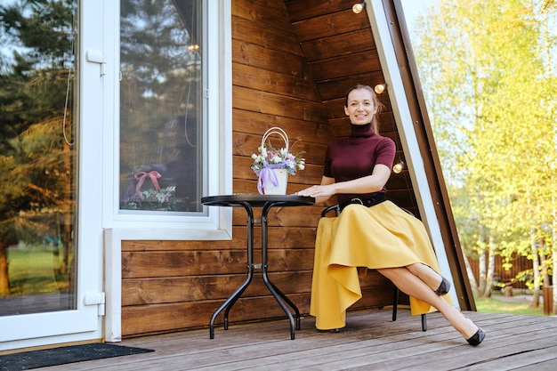 Photo happy smiling woman resting on terrace of tiny house