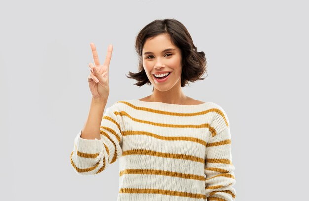 平和を示す幸せな笑顔の女性または2本の指