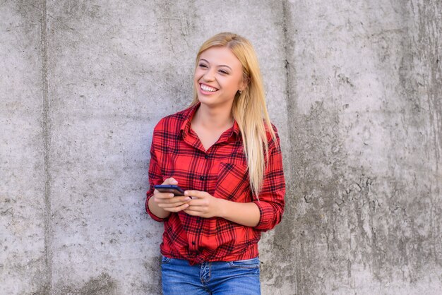 Happy smiling woman using her smartphone for typing with friend