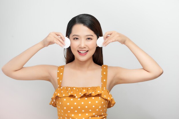 Happy smiling woman with cotton pad. Facial treatment, osmetology and skincare concept