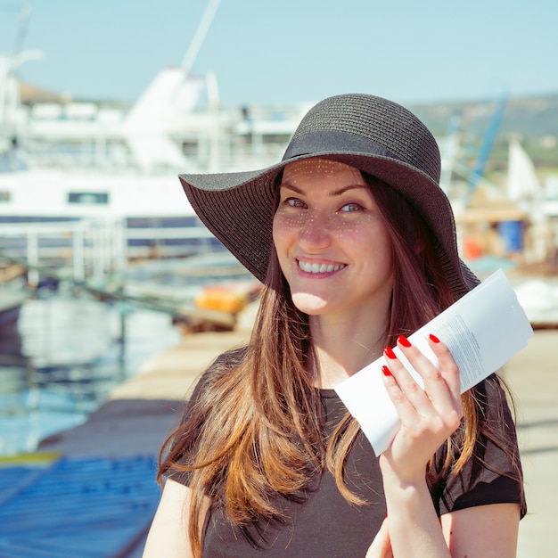 Happy smiling woman with tickets for the cruise at the port resort city.