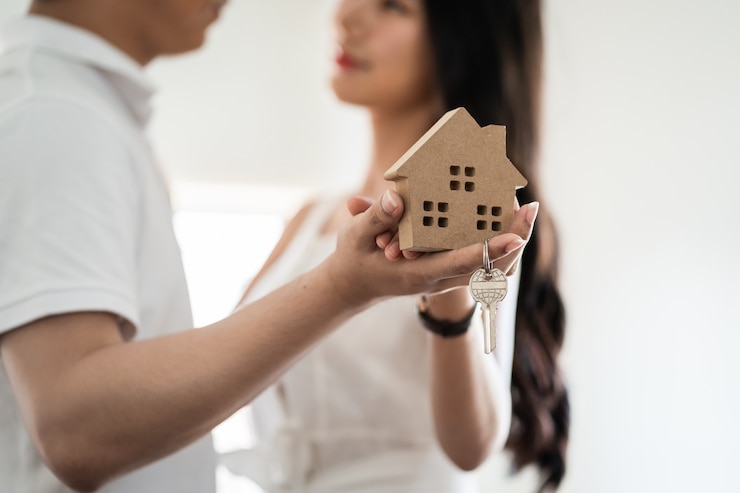 Photo happy smiling young asian couple holding a model house