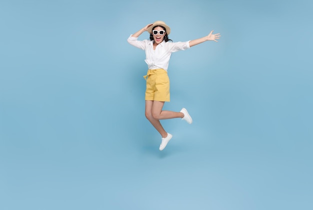 사진 블루 스튜디오 배경에 고립 된 여름 시간에 점프 행복 미소 젊은 아시아 관광 여자