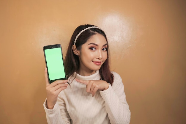 Happy and smiling young Asian women showing a green blank screen