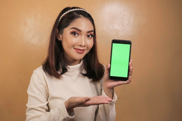 Happy and smiling young Asian women showing a green blank screen