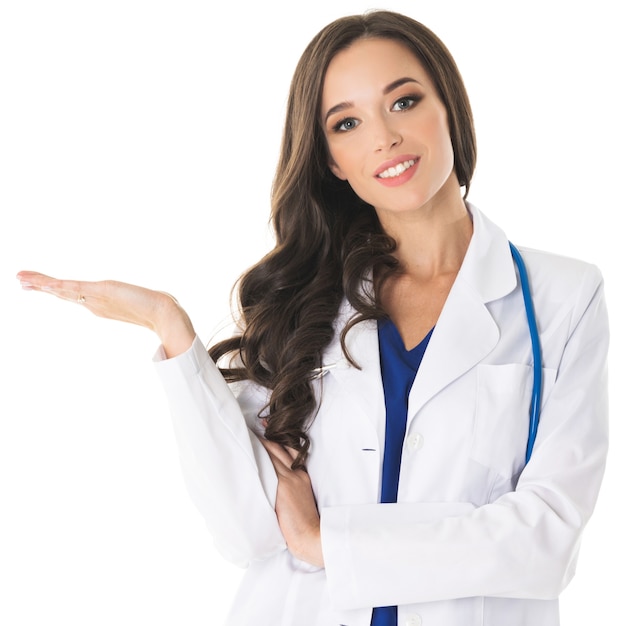 Happy smiling young beautiful female doctor showing blank area for sign or copyspace, isolated on white surface