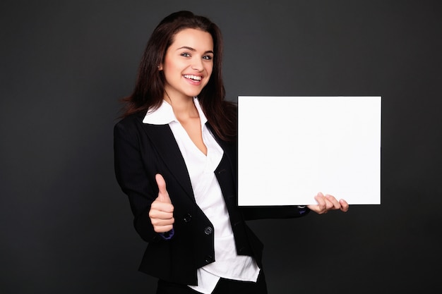 Happy smiling young business woman showing blank signboard