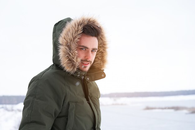 Happy smiling young caucasian man in fur hood Winter