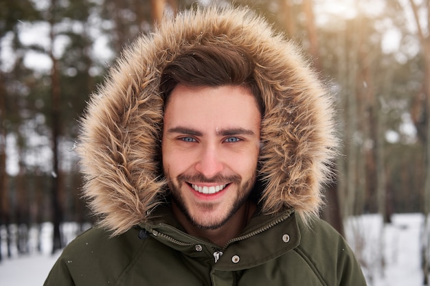 Happy smiling young caucasian man in fur hood Winter